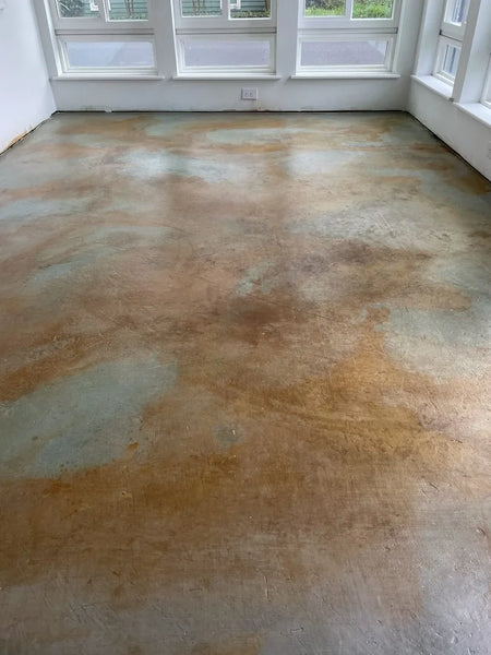 Image of a beautifully finished sunroom with Cola stained concrete floor accented with Seagrass, reflecting sunlight
