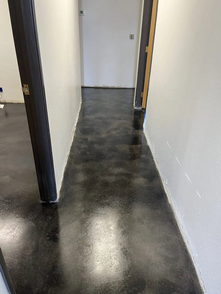 A smooth, polished concrete hallway floor stained in ColorWave Black and Steel, reflecting a sleek and modern look