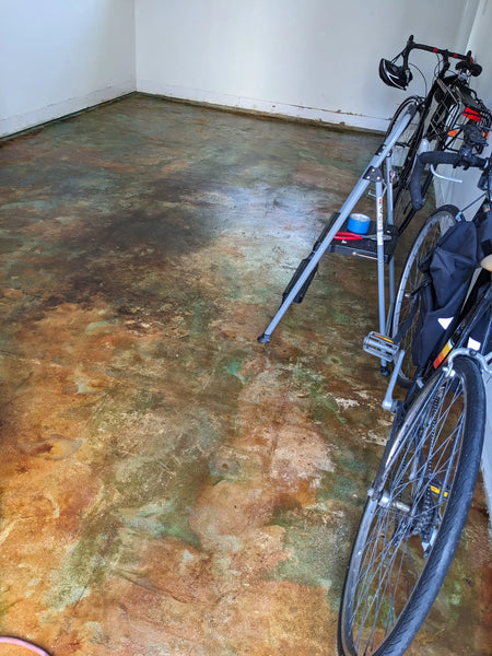 The finished concrete floor with a mix of earthy tones after sealing, with bikes and tools visible in the room