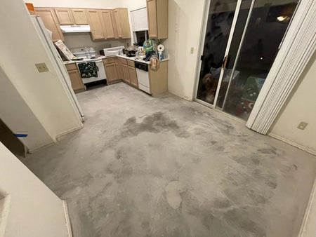 A picture showing a kitchen with bare, cleaned concrete floors after vinyl removal, showing the raw state before the acid staining process begins