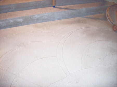 Using a trowel to create a swirling pattern on the surface of the wet concrete overlay