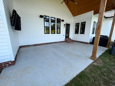 Unstained smooth-finish concrete on a covered new-construction farmhouse patio
