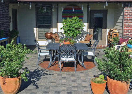 A circular paver design in warm terracotta hues is surrounded by charcoal Portico stained patio concrete pavers