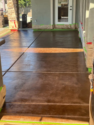 First coat of Driftwood EasyTint applied to a concrete patio with walls and columns masked for protection