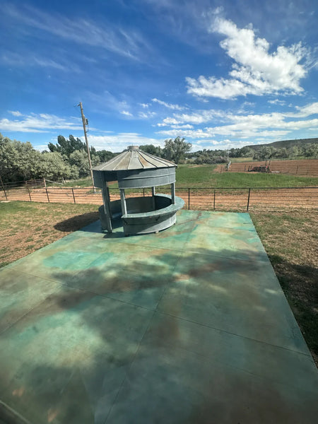 Concrete patio acid stained in turquoise and rust with Azure Blue and Coffee Brown EverStain, beside a repurposed grain-bin bar on a ranch