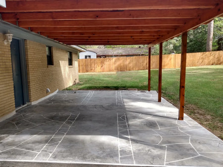 Masking tape laid out in a faux flagstone pattern on a smooth hand-troweled concrete patio before acid staining