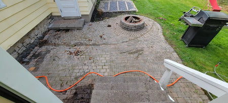 Neglected patio pavers covered with weeds, moss, and old sand