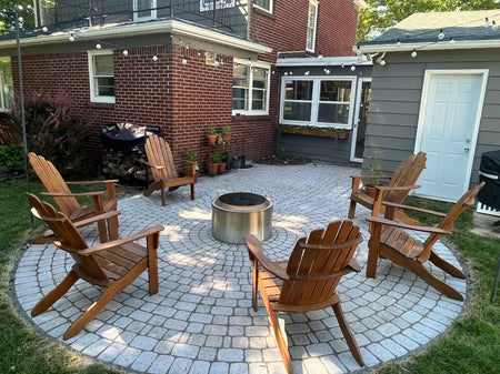 Whitewashed circular paver patio styled with a fire pit and wooden Adirondack chairs, finished in PaveWave White