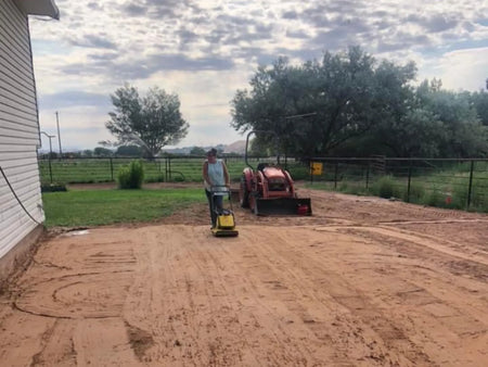 Compacting the graded dirt pad before pouring a new concrete patio