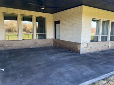 Black Antiquing Stain sprayed across a smooth covered concrete patio before applying the topcoat