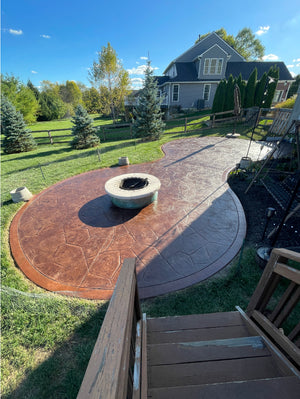 Stamped concrete patio with fire pit area finished in Aztec Brown and Russet border, showing rich color and glossy sealed surface