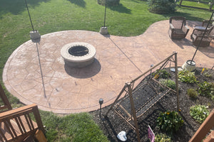 Faded stamped concrete patio with fire pit before restaining, showing dull color and surface wear