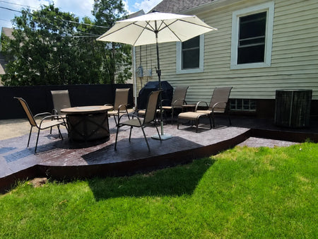 Backyard stamped concrete patio restored with Black and Charcoal Antiquing Stain and arranged with outdoor furniture