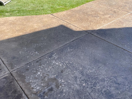 Colorado stamped concrete patio with freeze-thaw pitting, sun-faded color, and worn sealer