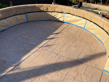 Previously integrally colored stamped concrete patio faded to pale pink and masked before applying Crimson Antiquing Stain