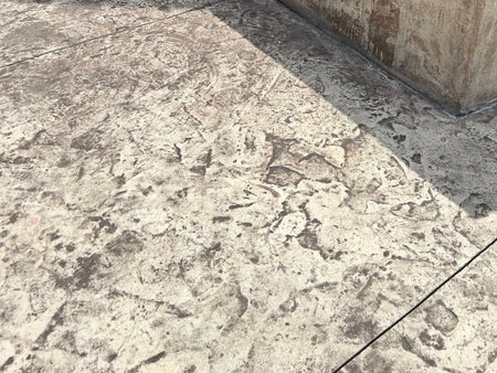 Close-up of a severely faded stamped concrete patio before applying Cumin Antiquing Stain