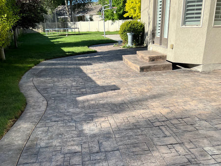 Faded and weathered 11-year-old stamped concrete patio before applying Chocolate EasyTint