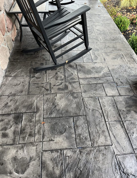 Close-up of a stamped concrete patio stained with ColorWave Steel, featuring a textured surface with rocking chairs on the patio