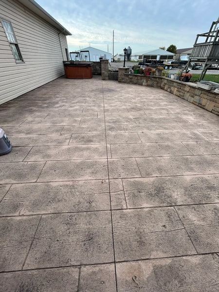 Faded gray-tan wood-plank stamped concrete patio with worn finish before Maple Antiquing stain