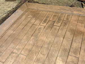 Freshly stamped wood-plank concrete patio in a plain wheat integral color before Antiquing stain