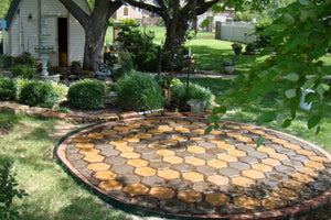Completed circular patio with Driftwood and Yukon Gold stained hexagonal pavers surrounded by lush landscaping