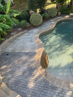 Midway photo depicting half of the pool deck revitalized with Charcoal stain and the remaining half in its pre-stain condition