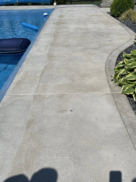 Before photo of a blotchy, stained swirled finish concrete pool deck