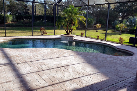 Faded concrete paver pool deck around a screened backyard pool before a Milano Red color update