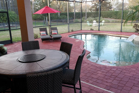 Screened backyard pool patio with Milano Red concrete pavers, lounge chairs, and patio table