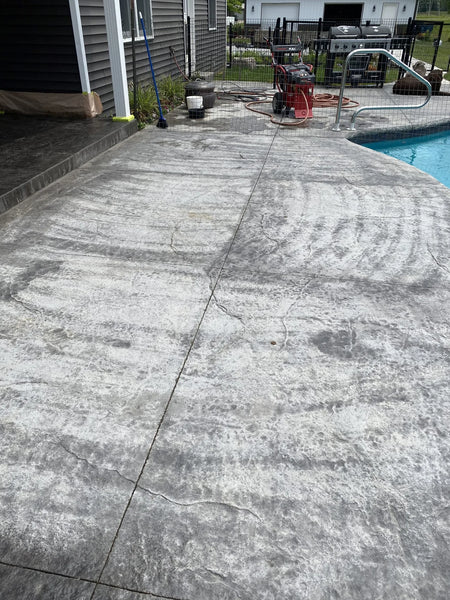 Damaged dark charcoal stamped concrete before restoration