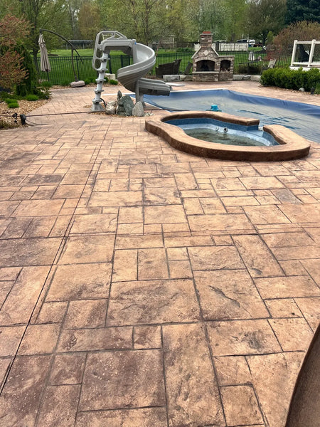 Faded stamped concrete pool deck surrounding a covered pool and raised spa before Yukon Gold EasyTint restoration