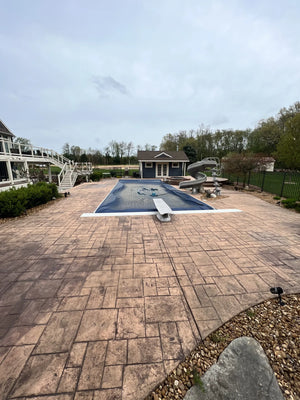 A faded stamped concrete pool deck, showing signs of wear and weathering