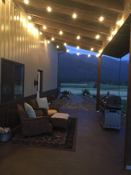 Furnished pole barn concrete porch stained with Driftwood Antiquing Stain and illuminated by string lights at dusk