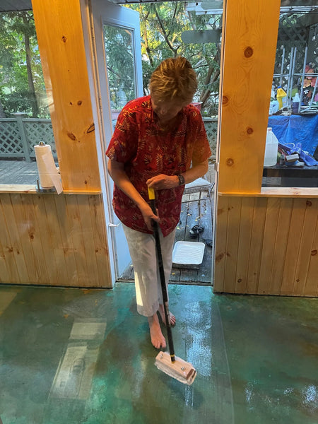 A woman applying ProWax Polish floor wax on the stained porch floor using a mop