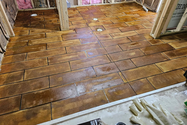 Concrete bathroom floor after Coffee Brown EverStain acid stain applied over a wood-plank tape stencil