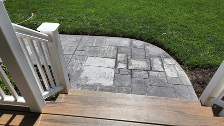 Close-up view of the worn-out stamped concrete sidewalk before renovation
