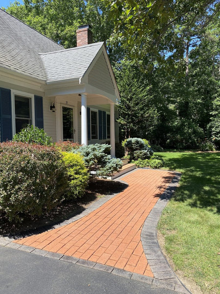 A stunning terracotta Portico stained paver walkway with a warm, earthy hue, featuring an outer edge stained with charcoal Portico paver stain