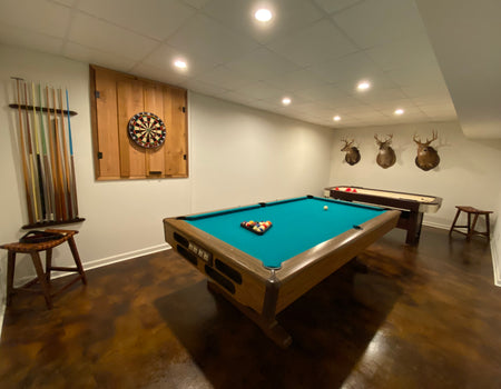 Renovated recreational room featuring an acid stained concrete floor, pool table, dartboard, and wall-mounted deer heads