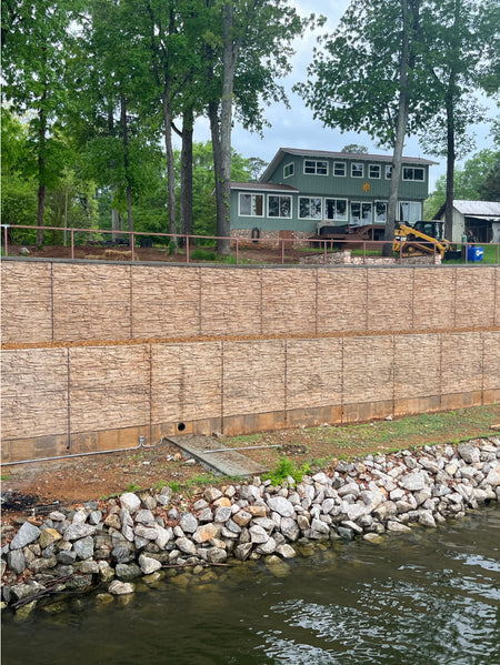 Large lakeside concrete retaining wall stained with Cafe Royale EasyTint™, featuring warm tan and brown tones that mimic natural stone under a tree-lined landscape