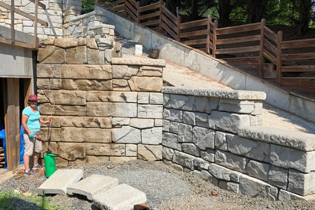 Homeowner using a pump sprayer to apply Cafe Royale EasyTint to a large textured concrete retaining wall