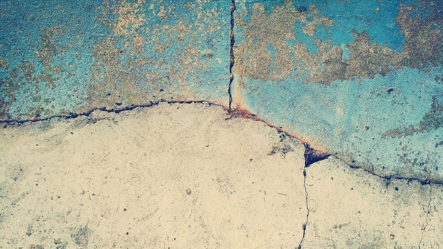 A grey and blue concrete slab cracked and rusted