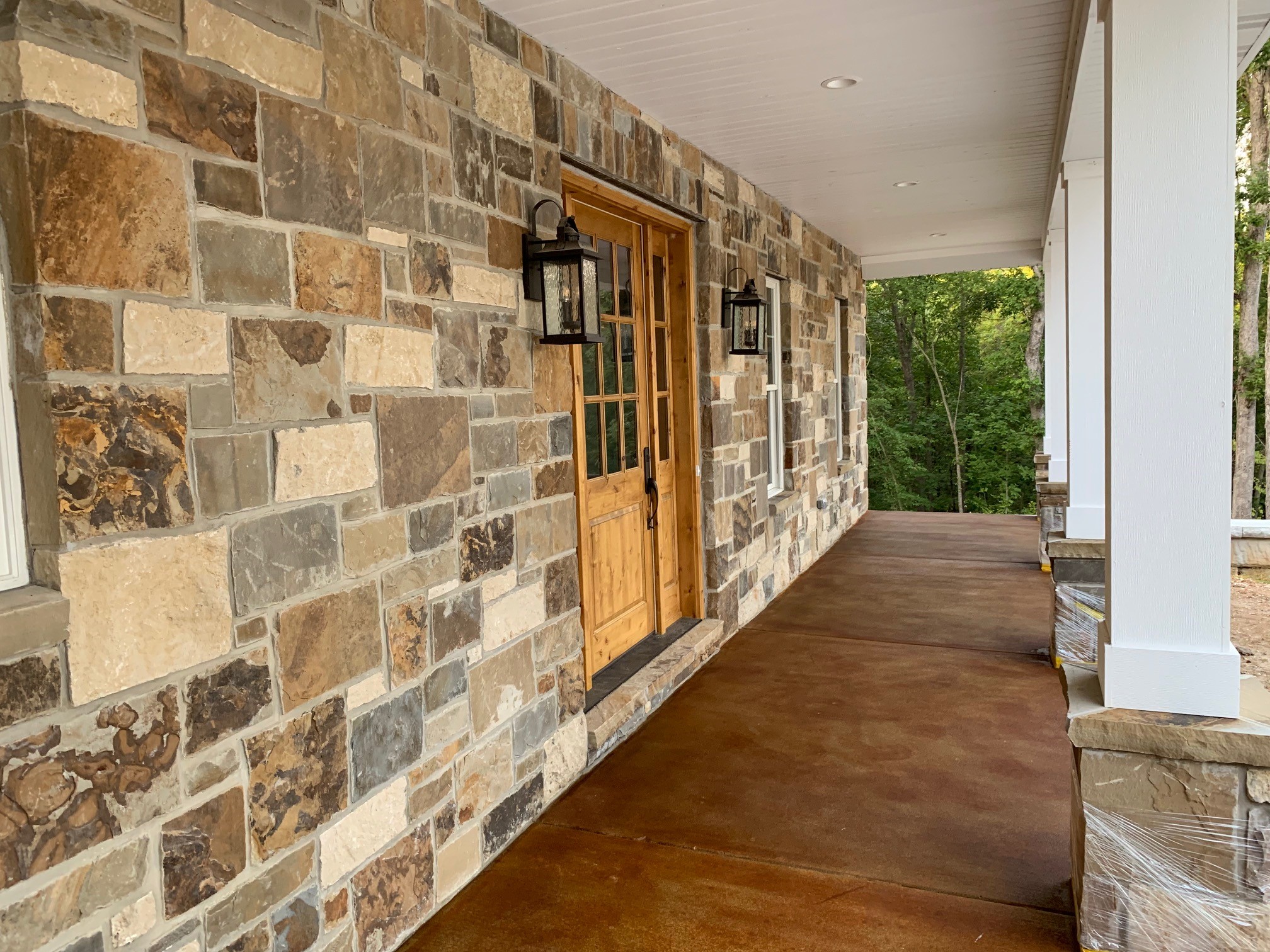 A finished front porch of an earthy brick estate home, enhanced by the warm hues of Cola EverStain™