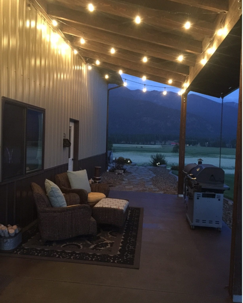 Pole barn patio with stained concrete floor lit up at night with string lights