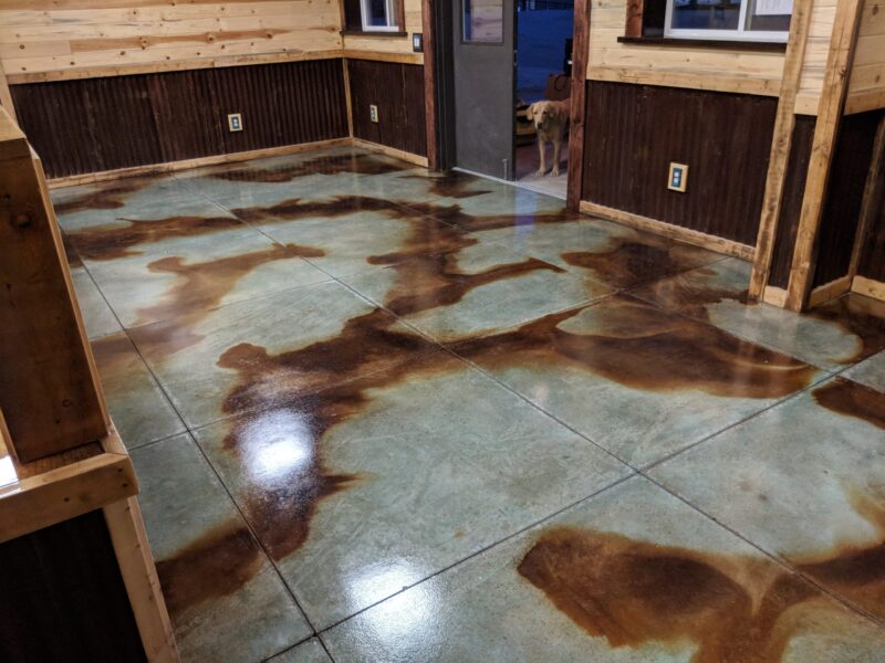 A newly stained concrete floor in a barndominium office with a marbled pattern of azure blue and coffee brown acid stains