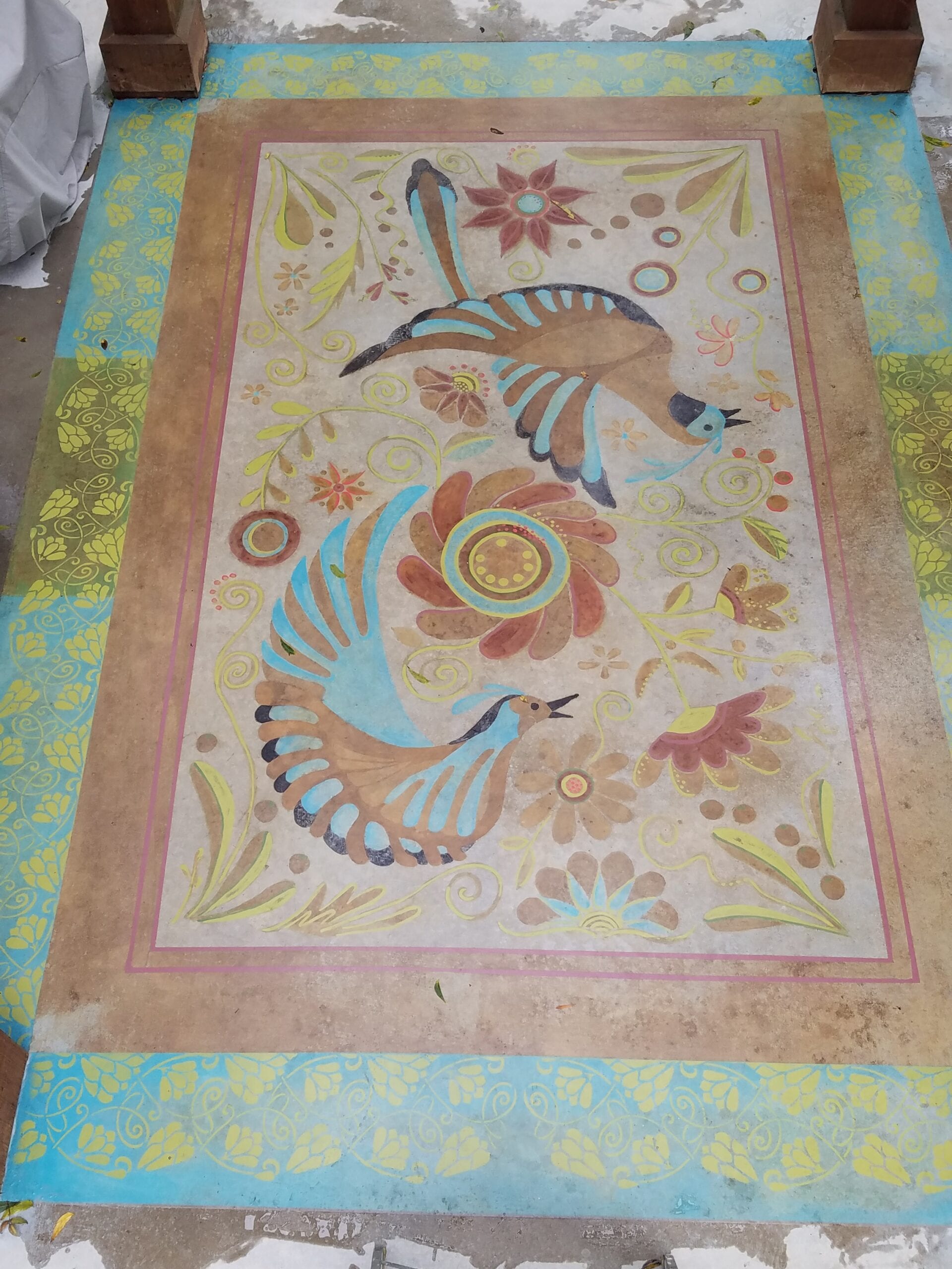 Concrete porch floor with a bird stencil design, made to look like a colorful rug using our DecoGel acid stains