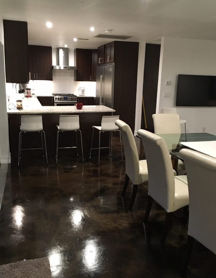 Modern condo floor after the application of coffee brown and black acid stains, showcasing a glossy wax finish that adds depth and durability to the unique and stunning design.