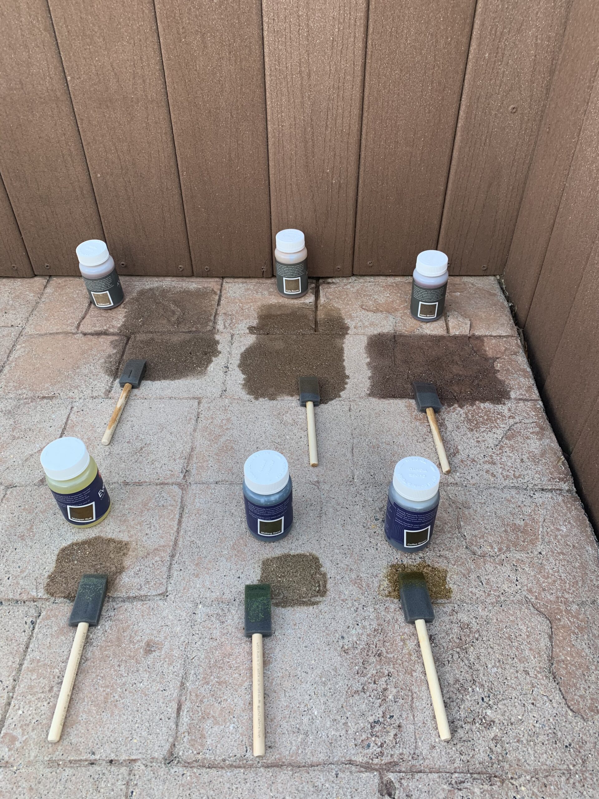 Image of a faded stamped concrete surface being tested with various Antiquing stain colors from a trial kit to find the perfect match