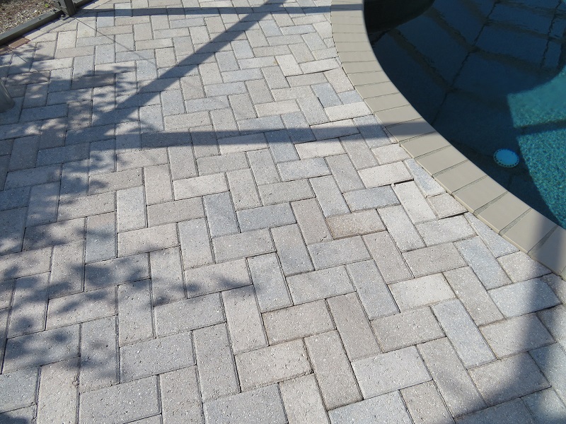 Unstained, faded multicolor pavers surrounding a swimming pool