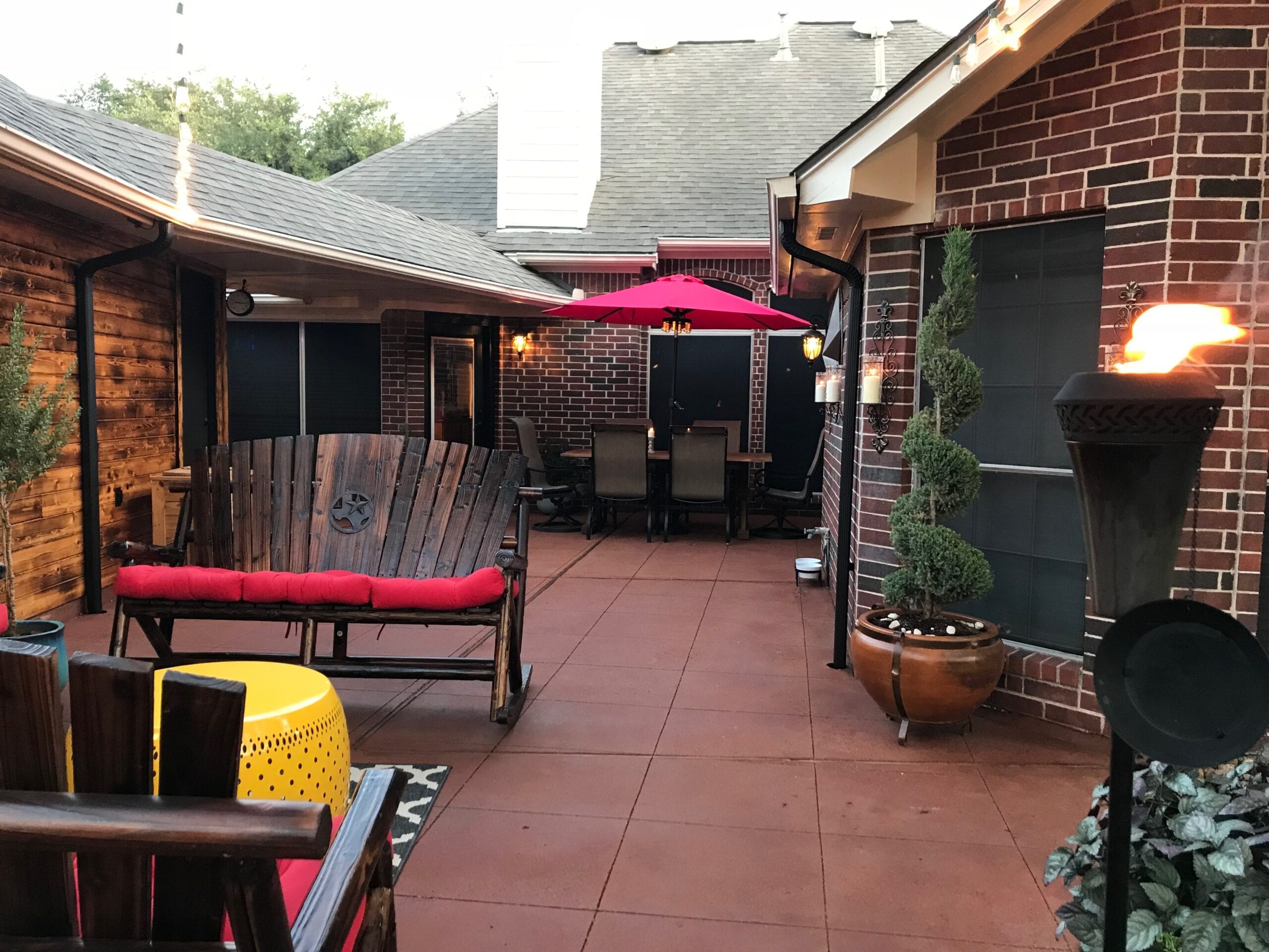 Image of a vibrant patio, stained with a blend of Milano Red, Driftwood, and Pumpkin Antiquing colors, adorned with red chairs and a yellow table