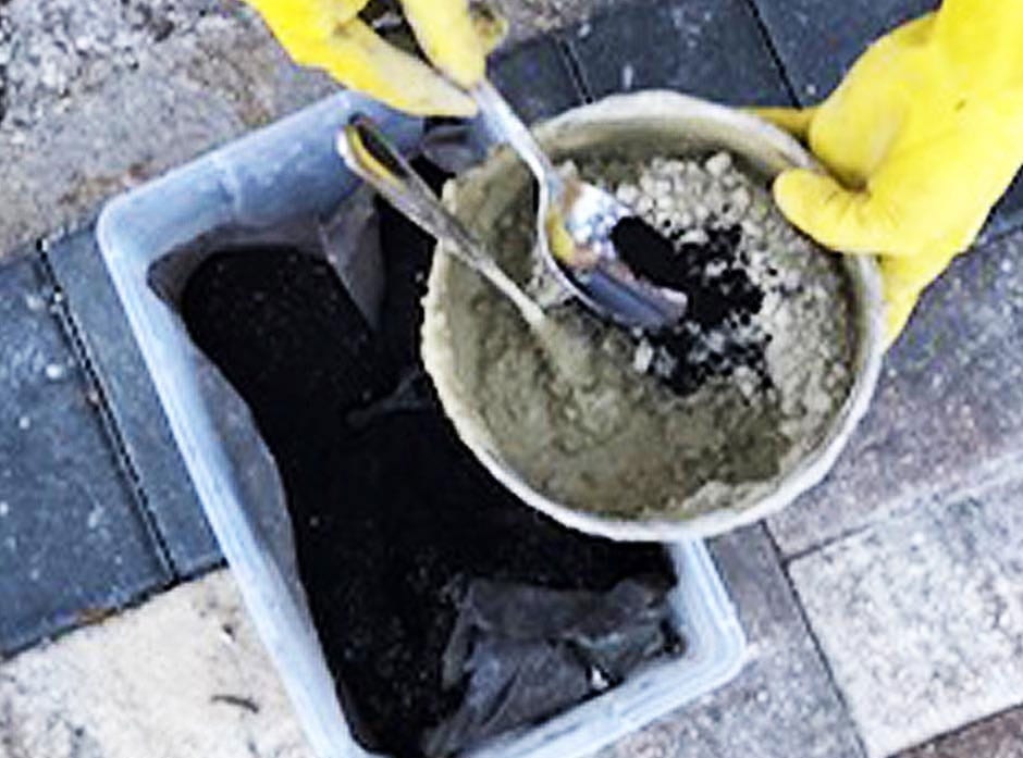 Person adding colored pigment into the concrete mix, stirring thoroughly to evenly distribute the color for a DIY project